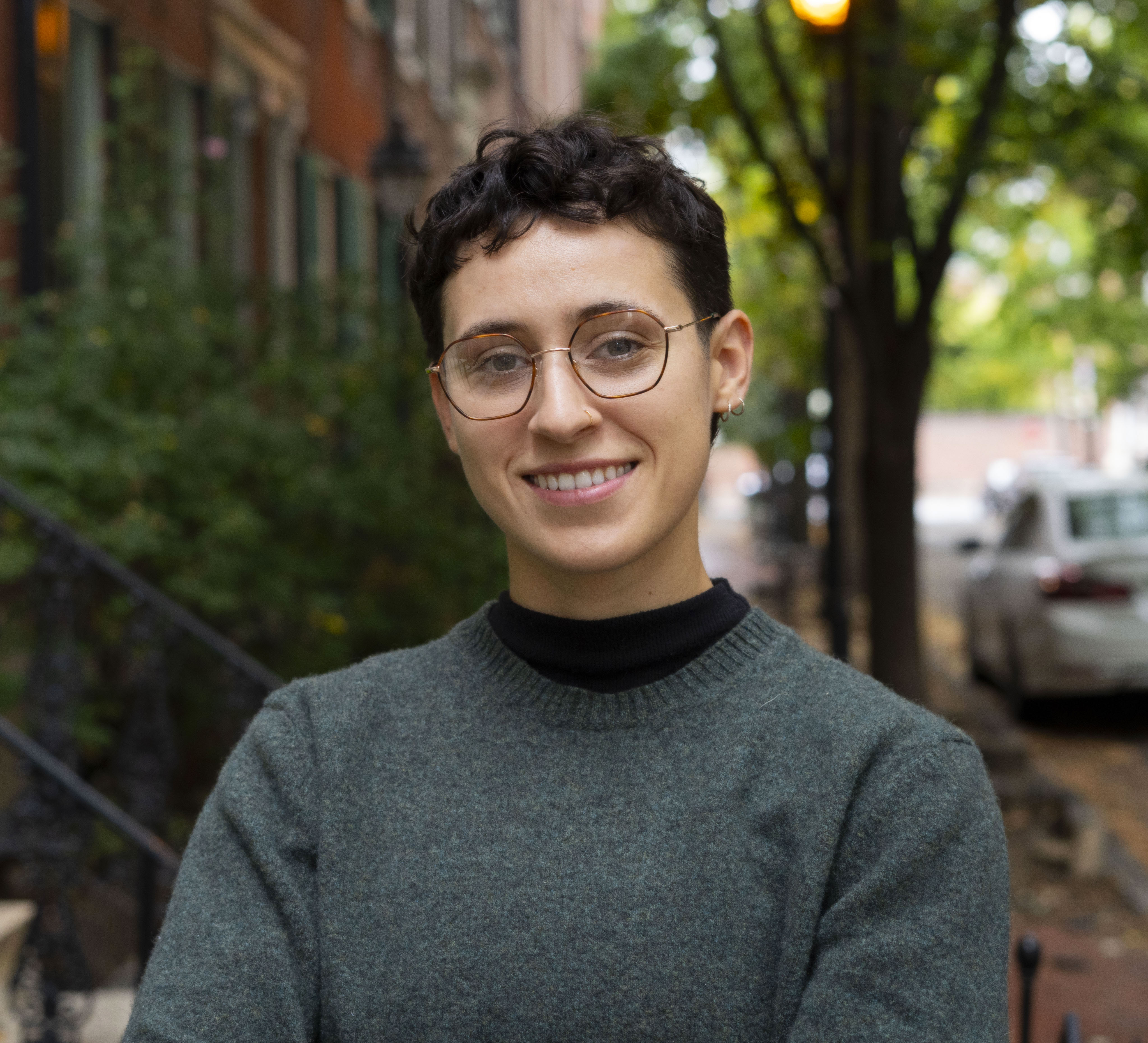 A photo of a young white person with glasses and short hair. 